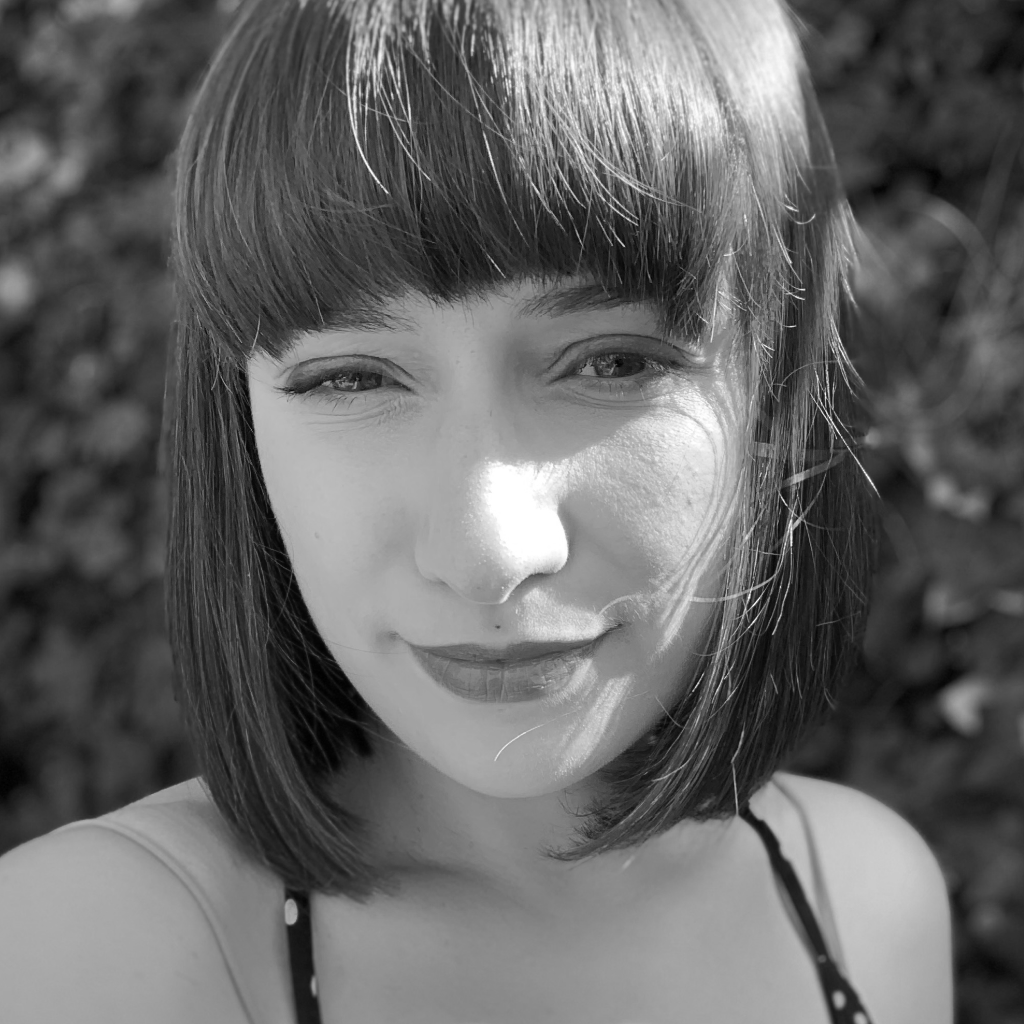 Portrait of a woman with brown hair on a flat gray background.